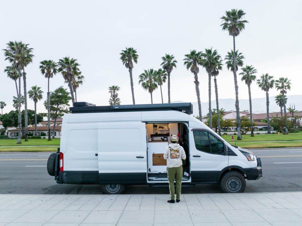 Ein Zustellspezialist steht vor einem weißen Lieferwagen, der für Expresslieferungen eingesetzt wird.