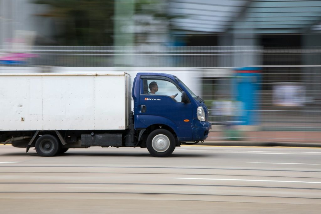 Ein blau-weißer europäischer Logistikwagen fährt tagsüber die Straße entlang.